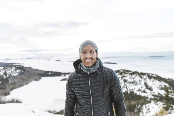 Happy young man standing outdoors on winter mountain resort - Valokuva, kuva