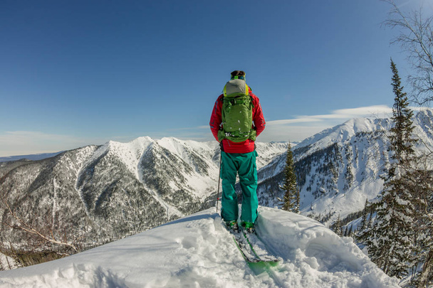 Man standing at top of ridge. Ski touring in mountains. Adventure winter freeride extreme sport - Valokuva, kuva