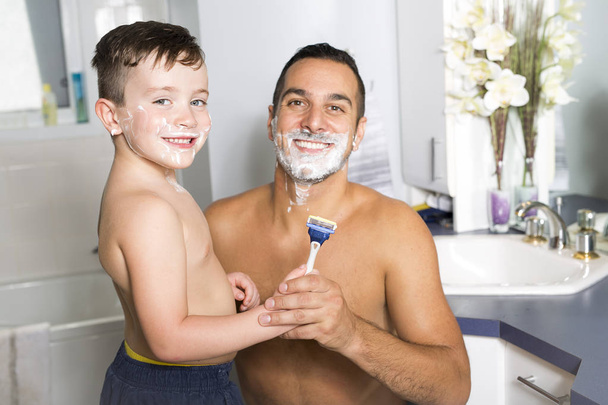 child have fun with dad shaving foam in the bathroom - Foto, imagen
