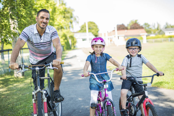 Dad With Daughter Son Riding Bikes In Park - Foto, Bild