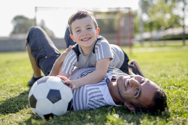 man with child playing football on field - Foto, Imagem