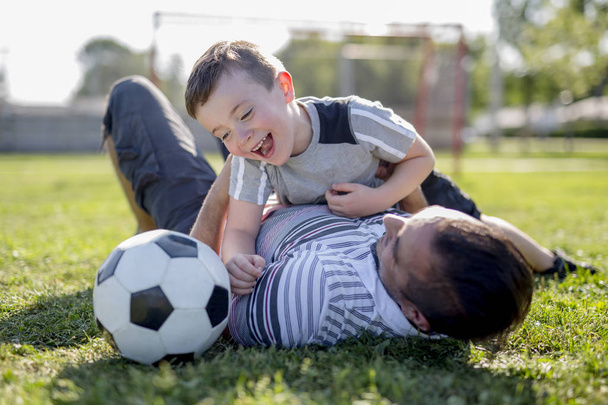 adam sahada futbol oynayan çocuk ile - Fotoğraf, Görsel