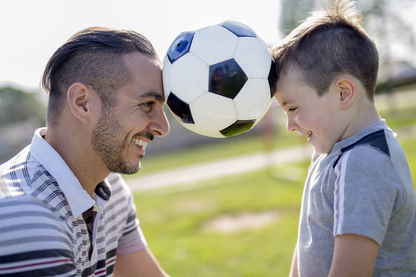 hombre con niño jugando al fútbol en el campo
 - Foto, Imagen