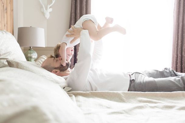 Father with adorable baby toddler on bed - Foto, Imagen