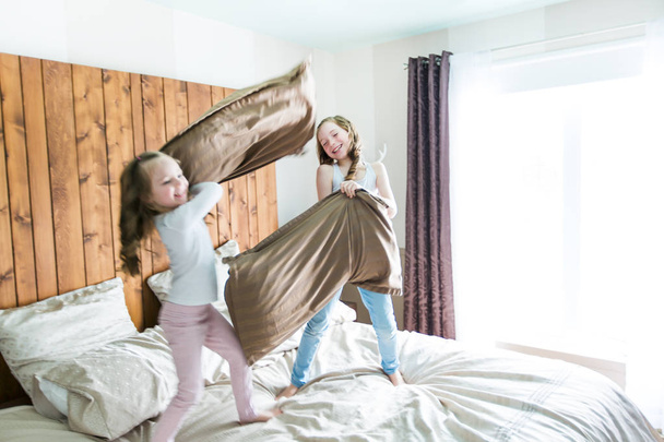 Portrait kids fighting with pillows in bed - Photo, Image