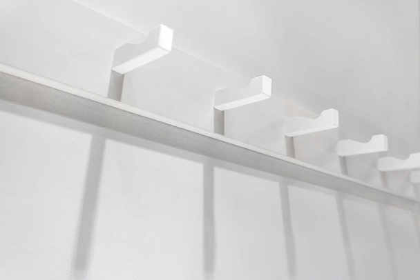 White wooden wall hanger mounted against white wall. - Foto, afbeelding