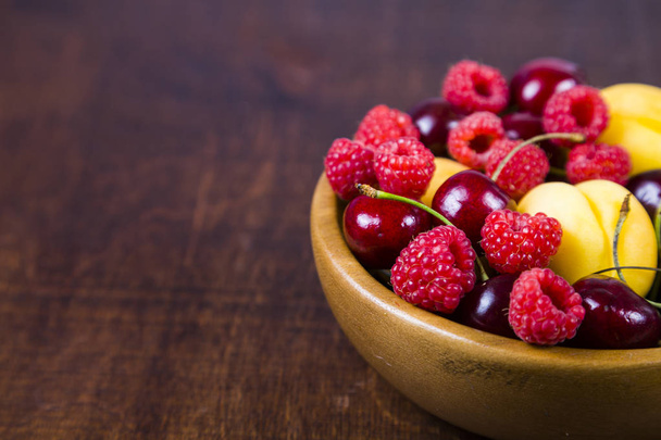 Ripe berries in a plate on a wooden table. - Fotoğraf, Görsel