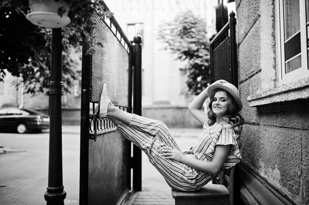Portrait of a fabulous young woman in striped overall and hat si - Фото, изображение