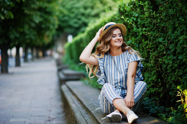 Portrait of a stunning young woman in striped overall sitting in - Foto, immagini