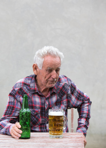 Vanhempi mies olutpullon ja mukin kanssa
 - Valokuva, kuva