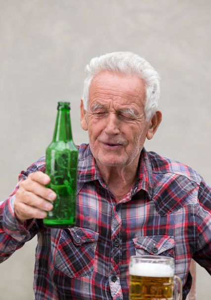 Senior man with beer bottle and mug - 写真・画像