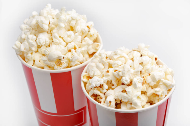 Popcornia punaisessa ja valkoisessa pahvilaatikossa. Popcornin raja eristetty valkoisella. Elokuva. Pikaruokaa. Maissi
 - Valokuva, kuva