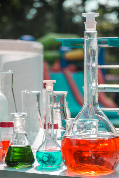 лабораторне обладнання на відкритому повітрі хімічний скляний посуд, наповнений барвистими рідинами
 - Фото, зображення