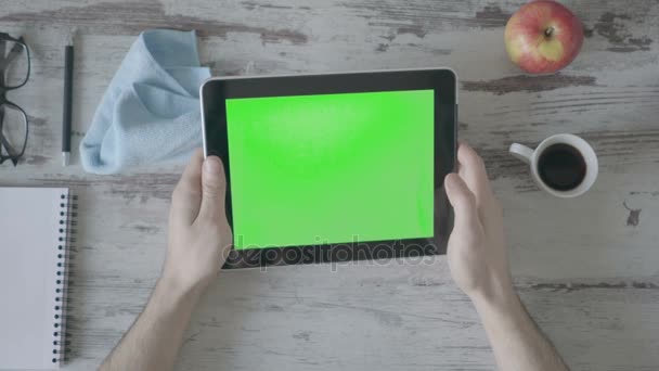 Hands holding tablet pc with green empty screen on wooden background - Footage, Video