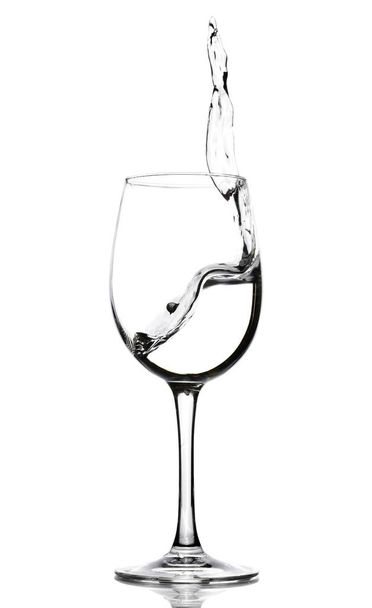 Een splash van kristal helder water in een glas voor wijn. Water spatten. Drinkwater. Alcohol. - Foto, afbeelding