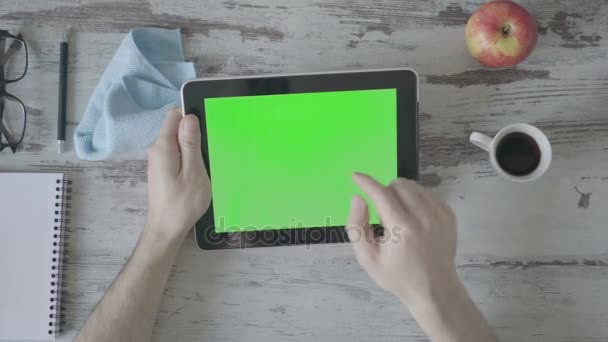 Mãos segurando tablet pc com tela verde vazia em fundo de madeira
 - Filmagem, Vídeo