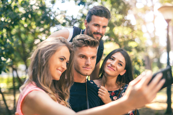 Groupe de quatre amis drôles prenant selfie avec un téléphone intelligent dans
  - Photo, image