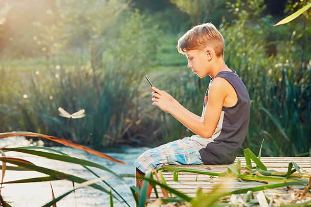 Petit garçon assis sur la jetée du lac
 - Photo, image