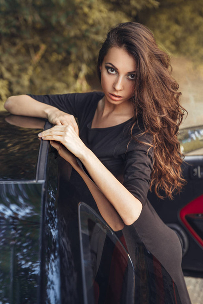 Beautiful brown hair young woman in black dress posing - Fotó, kép