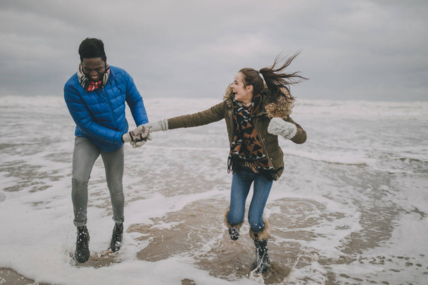 Young Couple Laughing In The Winter Beach Sea - 写真・画像