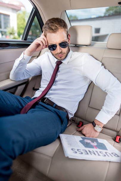 businessman in sunglasses with newspaper in car - Foto, afbeelding