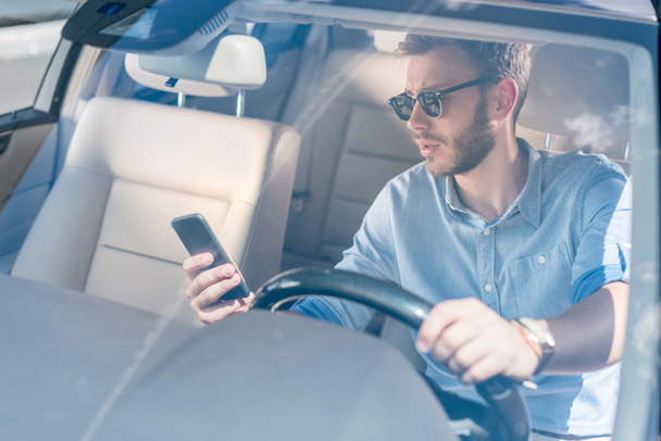 man with smartphone driving car - Фото, изображение