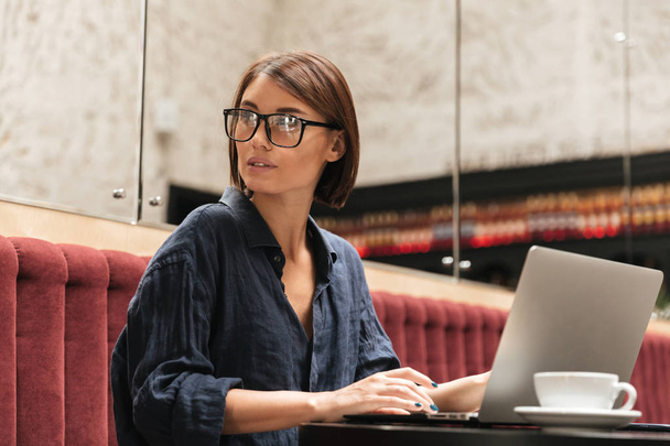 Side view of female manager in eyeglasses sitting by table - Foto, Imagem