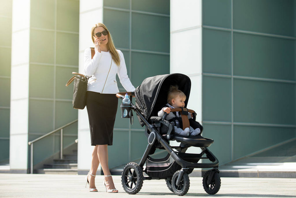 Business woman talking on the phone and pushing baby stroller - Zdjęcie, obraz