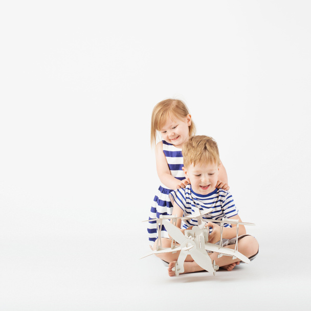 Petits enfants jouant avec jouet en papier avion assis sur le f
 - Photo, image