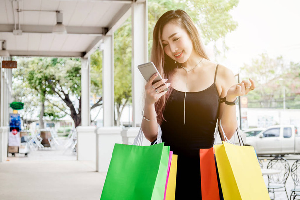 Woman using phone enjoying shopping Street - Foto, Imagen