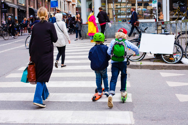 Funny children skate on the scooters at the crossroads - 写真・画像