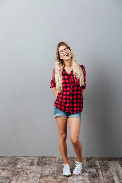 Thinking cheerful young blonde woman standing isolated - Фото, зображення