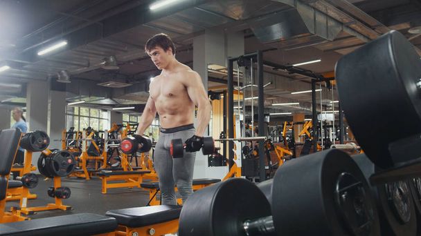 Muž sportovec zvedání činky bez košile v tělocvičně - Fotografie, Obrázek