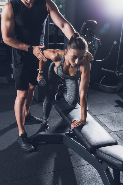 trainer helping woman to exercise with dumbbell - Photo, Image