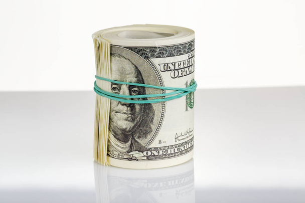Bundle of dollars tied with a rubber band stands upright - Фото, изображение