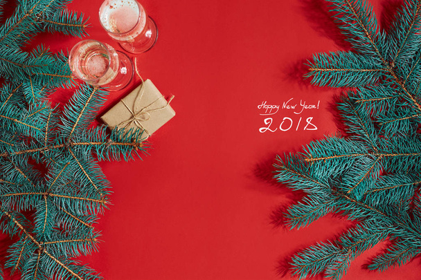 Two glasses of champagne with Christmas tree branch and small gift on a red background - Valokuva, kuva