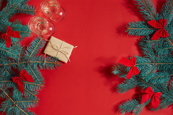 Due bicchieri di champagne con ramo di albero di Natale e piccolo regalo su sfondo rosso
 - Foto, immagini