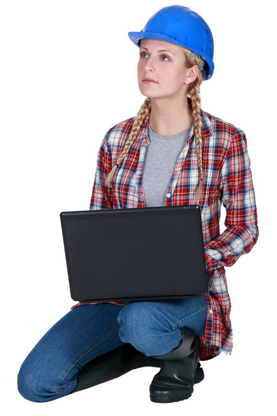 Blond builder kneeling with laptop - 写真・画像