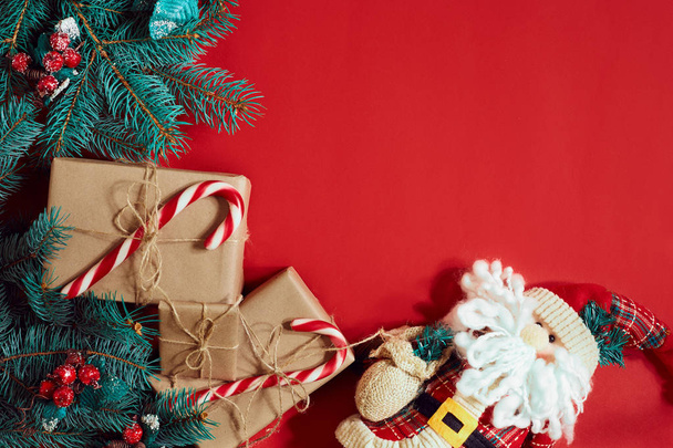 Kerst samenstelling van dennenappels, vuren takken en stapel geschenkdozen op rode achtergrond - Foto, afbeelding