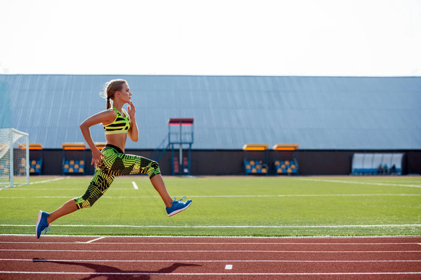 Koşu ve atletik yolda stadyum üzerinde çalışan güzel bir genç kadın egzersiz. - Fotoğraf, Görsel