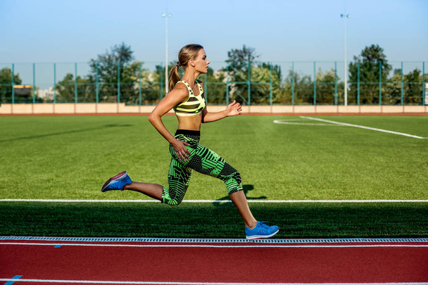 A female athlete runs along the treadmill. Sport background - Photo, Image