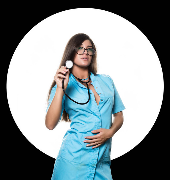 Sexy female doctor with stethoscope on a white circle and black background - Photo, Image