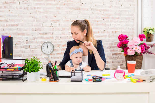 Mam en zakenvrouw werken met laptopcomputer thuis en spelen met haar baby girl. - Foto, afbeelding