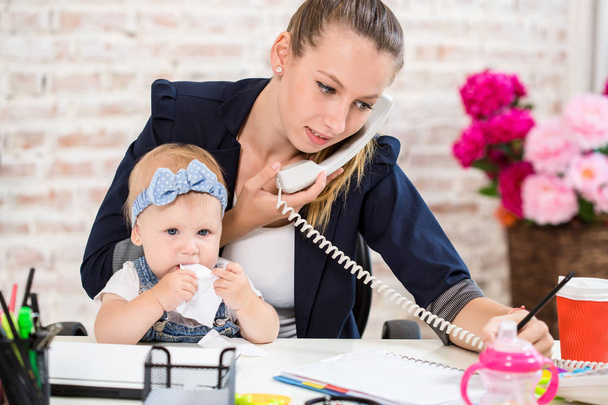 Family Business - telecommute Businesswoman and mother with kid is making a phone call - Photo, Image