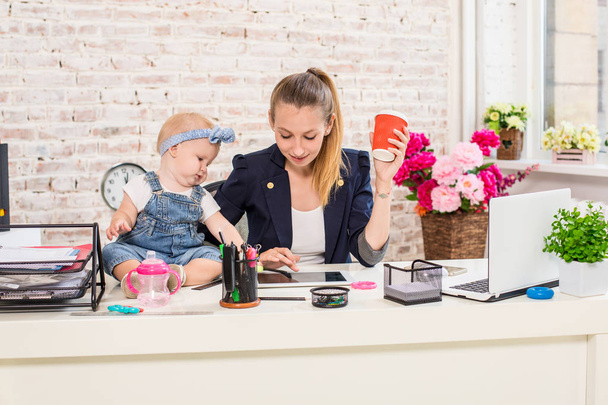 Maman et femme d'affaires travaillant avec un ordinateur portable à la maison et jouant avec son bébé fille
. - Photo, image