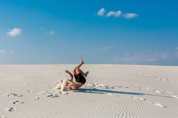Sportif delikanlı istiyorum Nehri yakınında kum üzerinde akrobatik egzersizleri yapıyor - Fotoğraf, Görsel