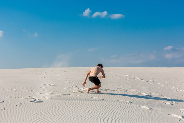Sportieve jongeman wilt doen acrobatische oefeningen op het zand in de buurt van rivier - Foto, afbeelding