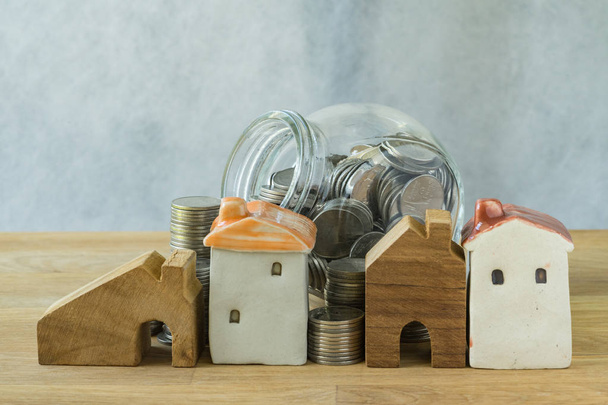 miniature house with stack of coins and coins in glass jar as fi - Fotoğraf, Görsel