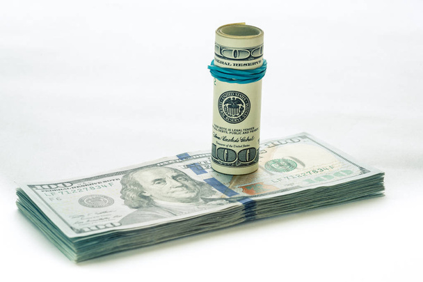 Una banconota da 100 dollari arrotolata che poggia su un'altra banconota da 100 dollari angolata isolata su sfondo bianco
 - Foto, immagini