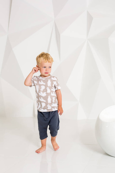 niño pequeño en una camiseta y pantalones cortos sobre un fondo blanco
 - Foto, Imagen